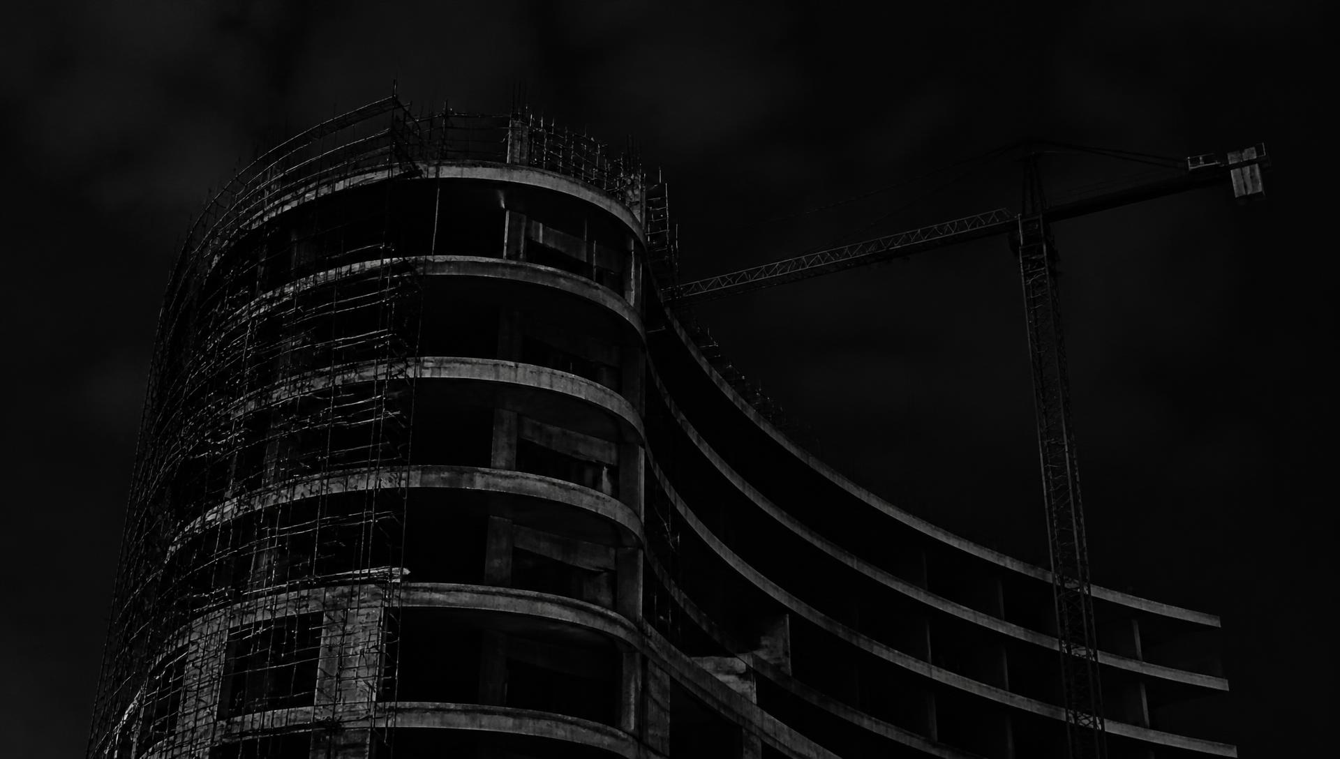 Curved concrete building under construction at night